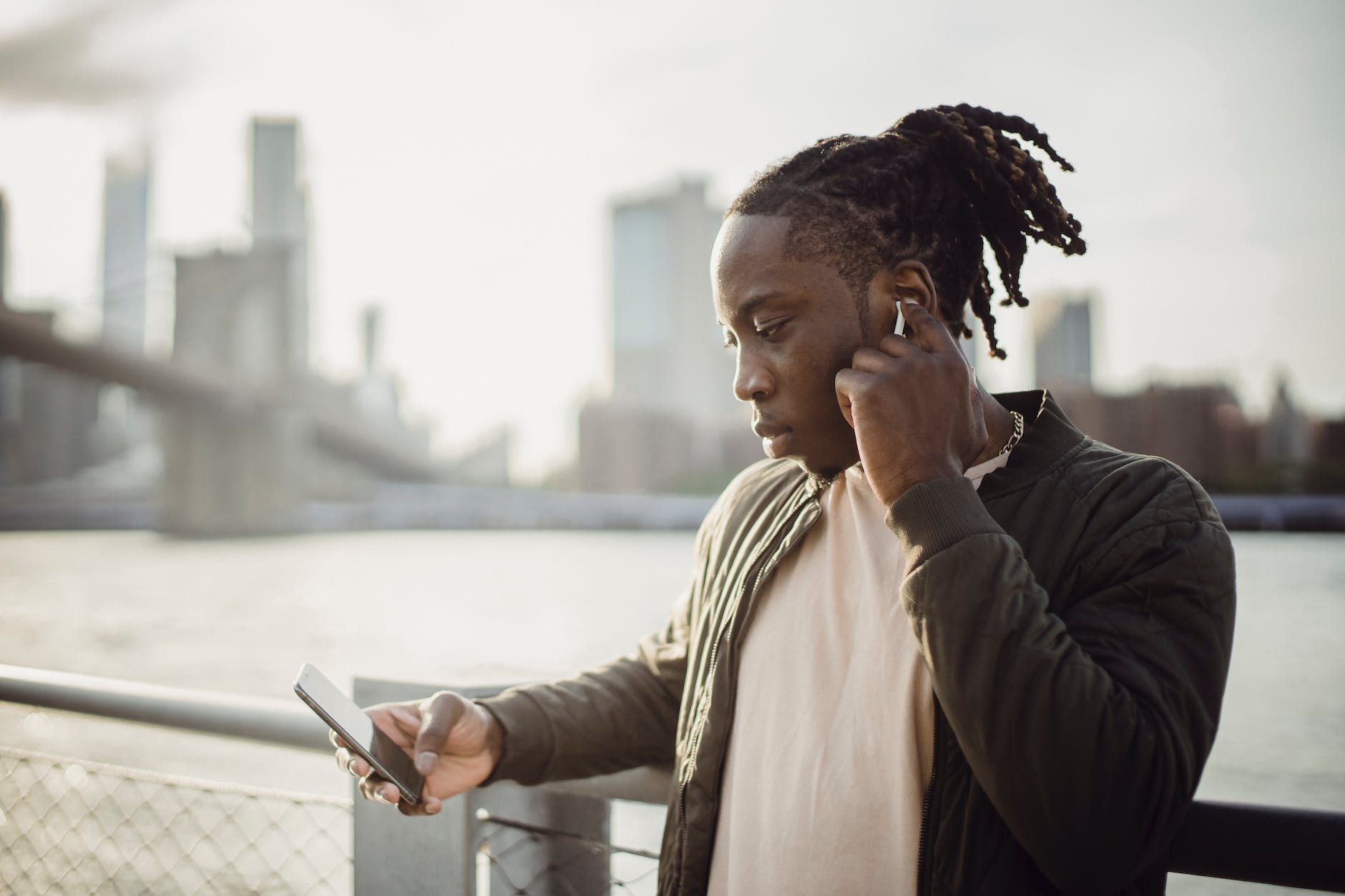 melancholic black man with smartphone listening to music in earphones